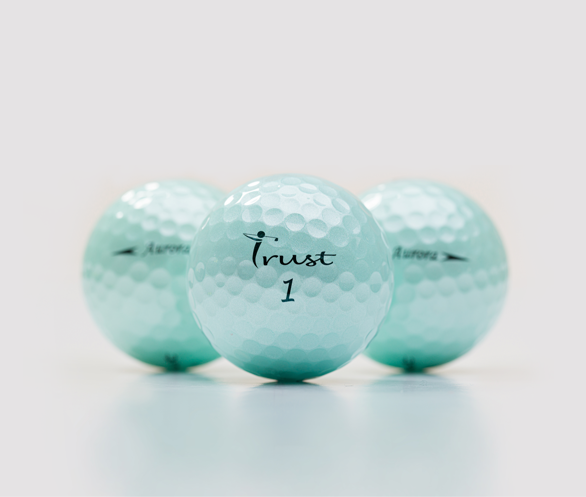 Three light blue golf balls with branding on a white background